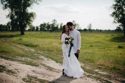 Bride and bridegroom standing on field