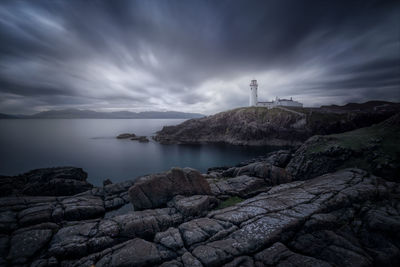 Lighthouse by sea against sky