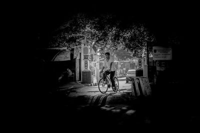 Man riding bicycle against trees in city