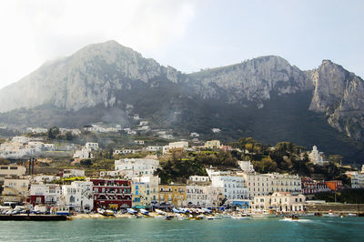 Boats moored at harbor by mountains against sky