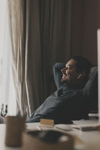 Smiling businessman with wireless in-ear headphones taking rest at office