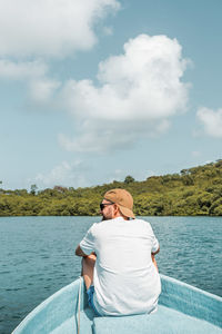 Rear view of man standing by lake against sky