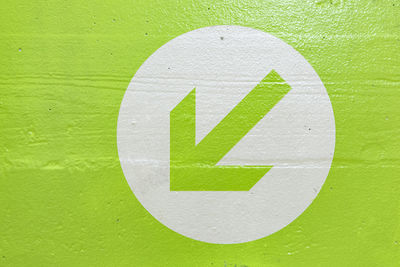 Close-up of arrow sign on green wall