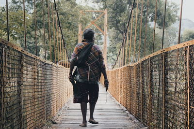 Rear view of man walking on footbridge