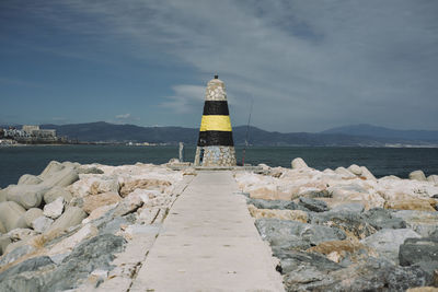 Rear view of rock by sea against sky