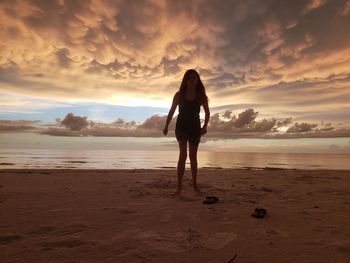 Rear view of man standing on beach during sunset