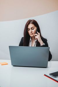 Young woman using phone while sitting on table