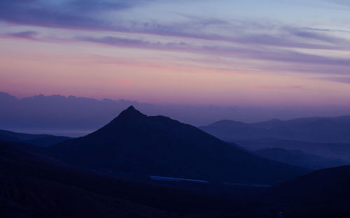 Scenic view of silhouette mountains against romantic sky at sunset