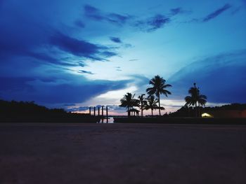 Silhouette palm trees on beach against sky at sunset