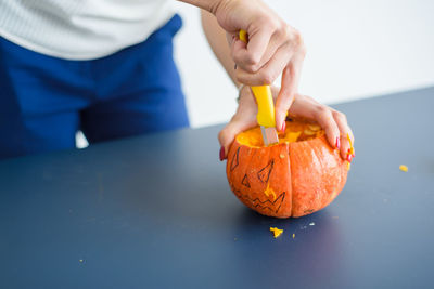 Midsection of man holding pumpkin on table