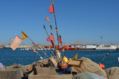 Buoys and fishing nets at harbor against clear sky