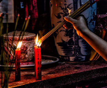 Close-up of hand with illuminated candles