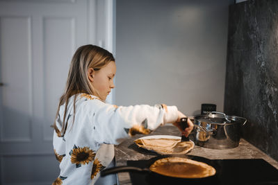 Girl in kitchen preparing pancakes