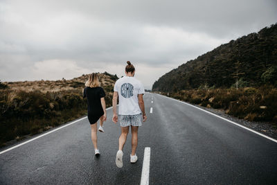 Rear view of people walking on road against sky