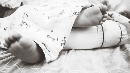 Low section of baby lying on bed