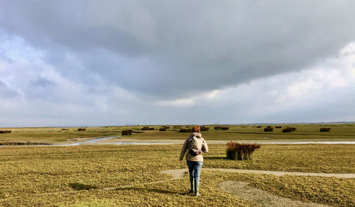 Rear view of man standing on field against sky