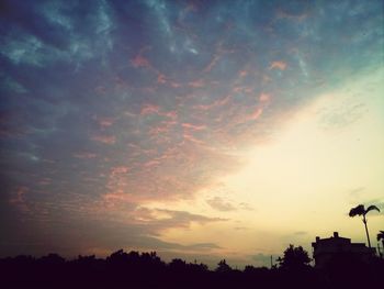 Silhouette of trees against cloudy sky