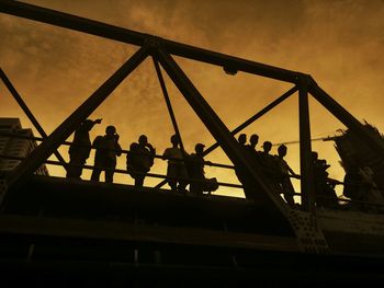 Low angle view of silhouette men on bridge against sky