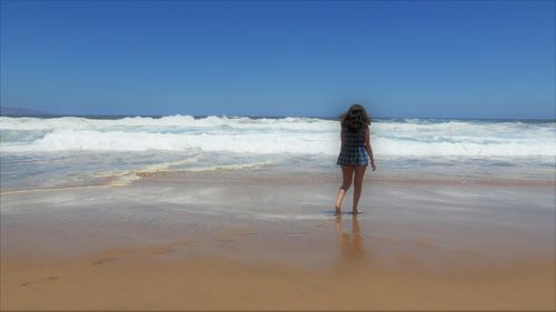 Woman walking on beach against clear sky