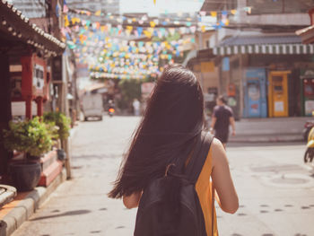 Rear view of woman standing on street in city