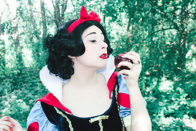 Portrait of woman with red umbrella against trees