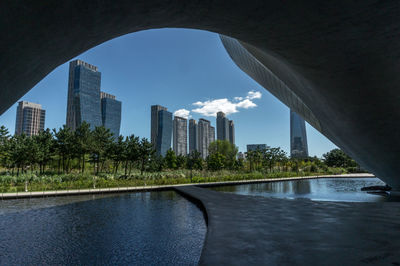 Arch bridge over river amidst buildings against sky