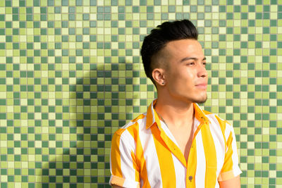 Portrait of young man looking away against wall