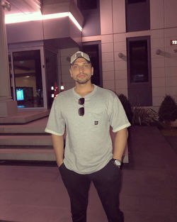 Portrait of young man standing against illuminated building