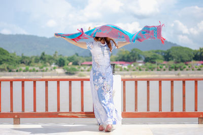 Woman with umbrella standing by railing