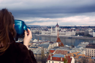 Woman photographing through arch bridge in city