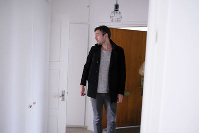 Man looking away while standing by door at home