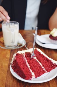 Midsection of person with coffee sitting in front of cake