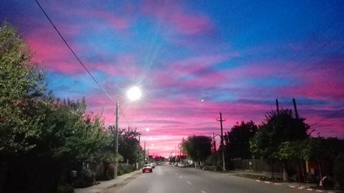 Cars on road against sky at sunset