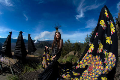 Portrait of young woman standing against sky