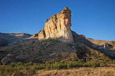 Rock formations on landscape against clear blue sky