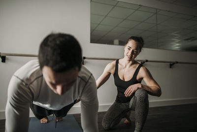 Female personal trainer coaches male client doing push ups