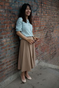 Portrait of smiling woman standing against brick wall