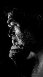 Close-up of man looking away against black background