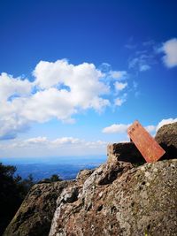 Low angle view of rocks by sea against blue sky