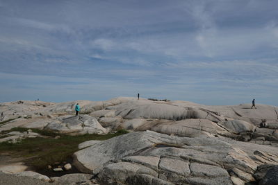 People on rock against sky