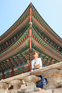 Low angle view of woman sitting against building