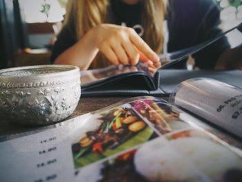 Midsection of woman with menu at table in restaurant