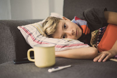 Portrait of ill boy lying on sofa at home