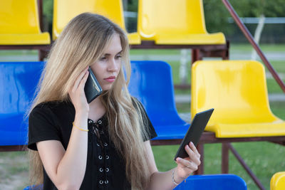 Young woman talking through mobile phone while sitting on chair