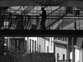 Side view of silhouette man standing by railing against building