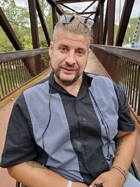 Portrait of young man sitting on railing