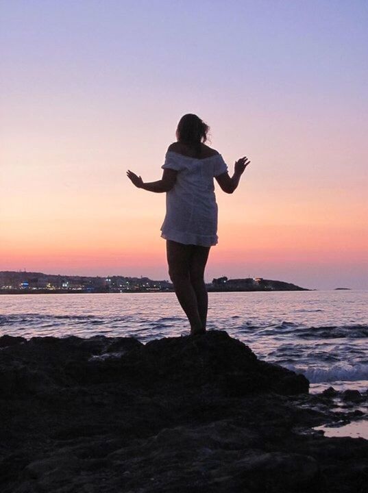 sunset, full length, sea, water, lifestyles, standing, leisure activity, orange color, sky, beach, shore, scenics, tranquil scene, beauty in nature, silhouette, tranquility, horizon over water, copy space