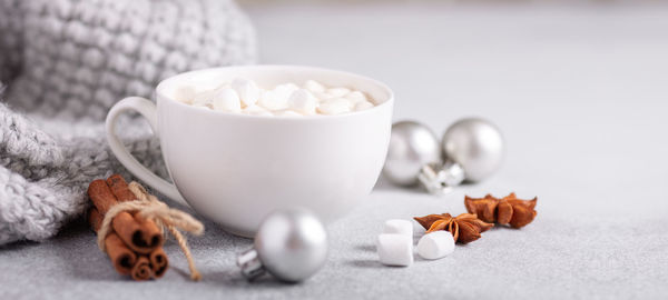 White cup with coffee and marshmallow, sweater, cinnamon. cozy christmas composition. hygge concept