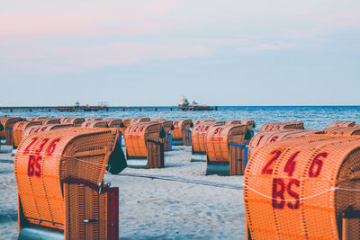 Hooded chairs on beach against sky