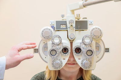 A male ophthalmologist checks a girl's eyesight using a phoropter. vision treatment